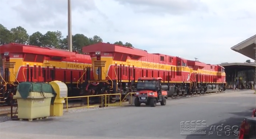 Red-and-yellow painted Florida East Coast locomotives paused in a yard.