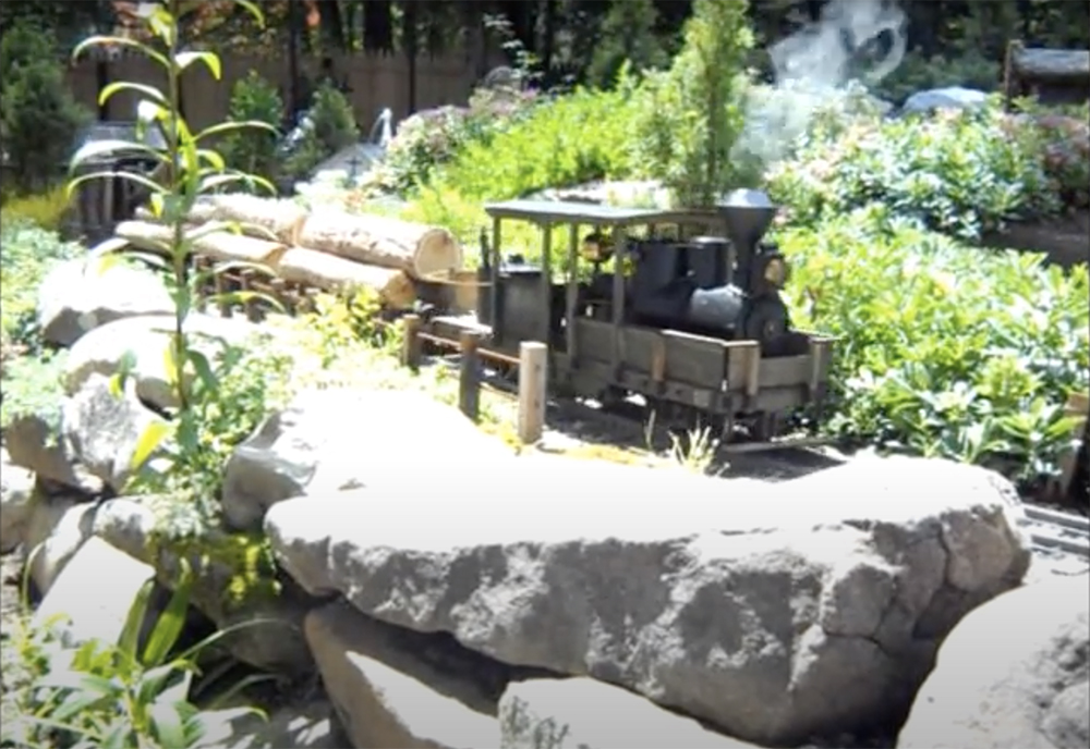 train carrying logs on a garden railroad