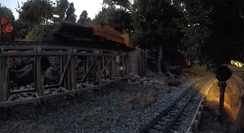 trains running on a garden railroad at twilight