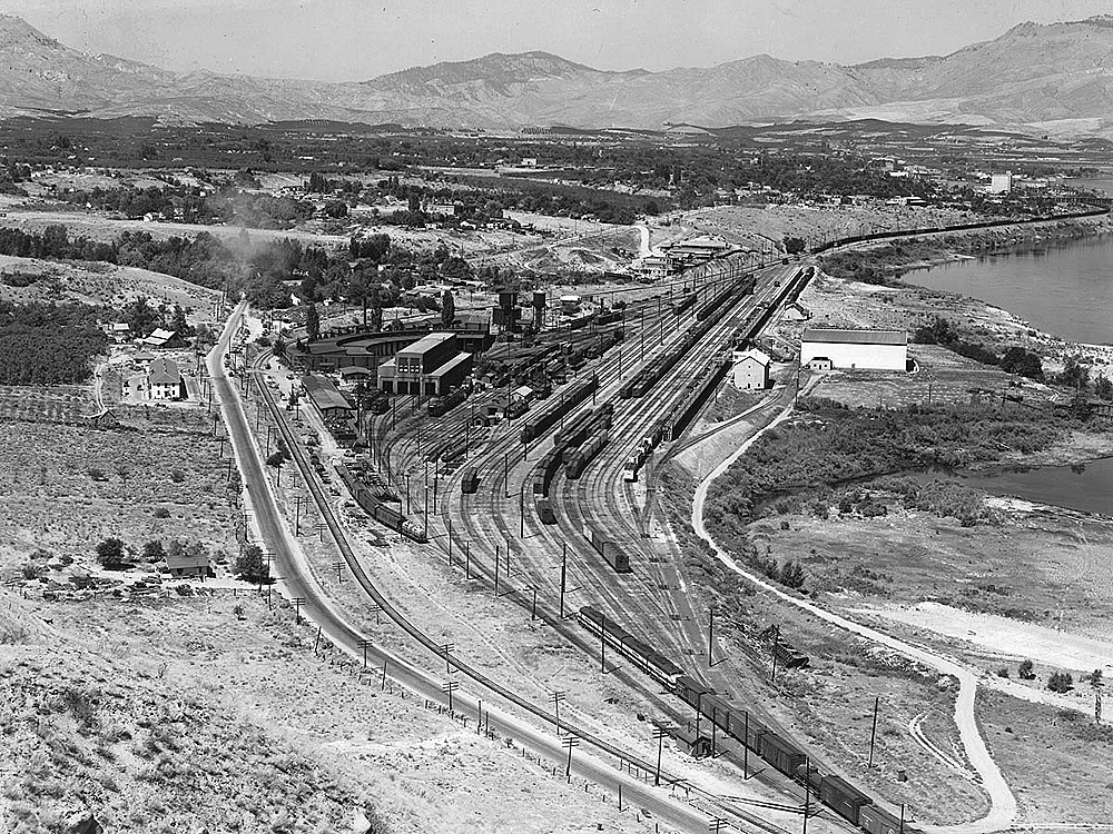 Bird's eye view of a rail yard in a mountain valley town.