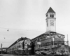 Several trains paused near a train station with large clocktower.