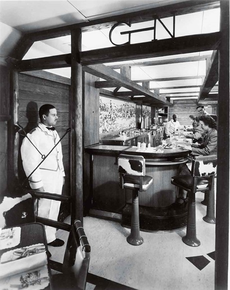 People seated at a bar and a white-suited waiter standing by.