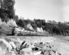 Diesel locomotive-led passenger train seen near a sandy beach.