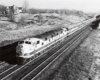 Diesel-locomotive led passenger train bends toward the photographer on a four-track mainline.