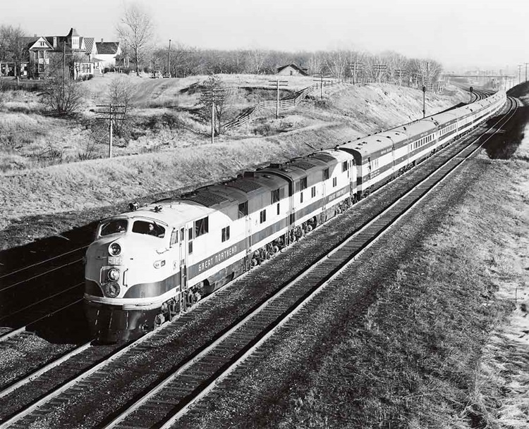 Diesel-locomotive led passenger train bends toward the photographer on a four-track mainline.