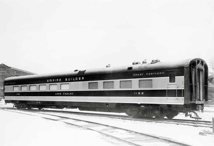Angled side view of a passenger car in a rail yard.