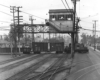 A freight cross a complicated track diamond just underneath a signal bridge.