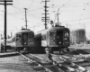Two electric interurban passenger trains pass each other on complicated track work.