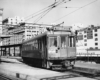 Streetcar departs a terminal on elevated tracks in a city scene.