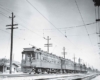 Five connected streetcars or electric interurbans caught moving with a motion-blurred photograph.