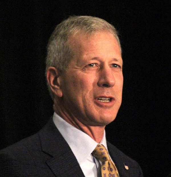 Man in coat and tie speaking