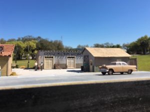 Model buildings with a car and people standing outside
