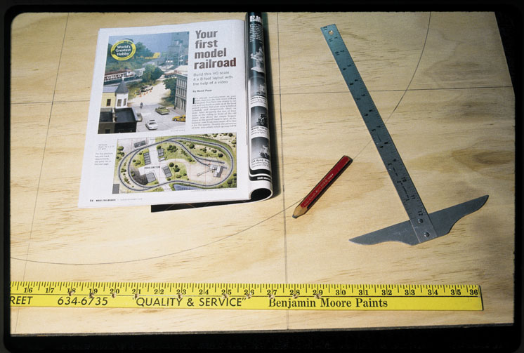 A drywall T-square with measuring tape on benchwork