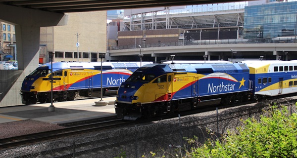 Trains at station with baseball stadium in background