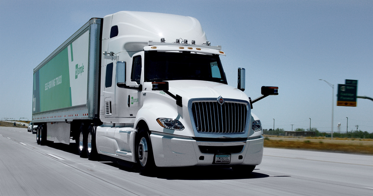 White semi-truck with trailer on a major highway under cloudless skies.