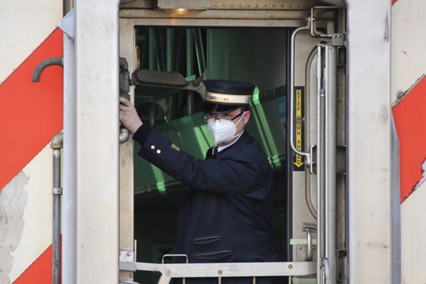 A train conductor wearing a mask