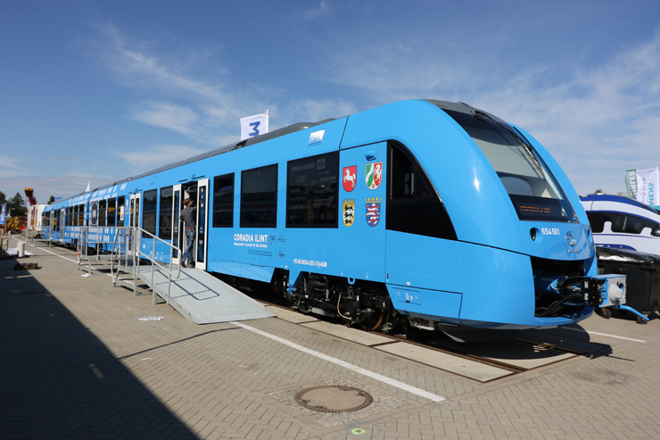 A blue-painted passenger train under mostly clear skies.