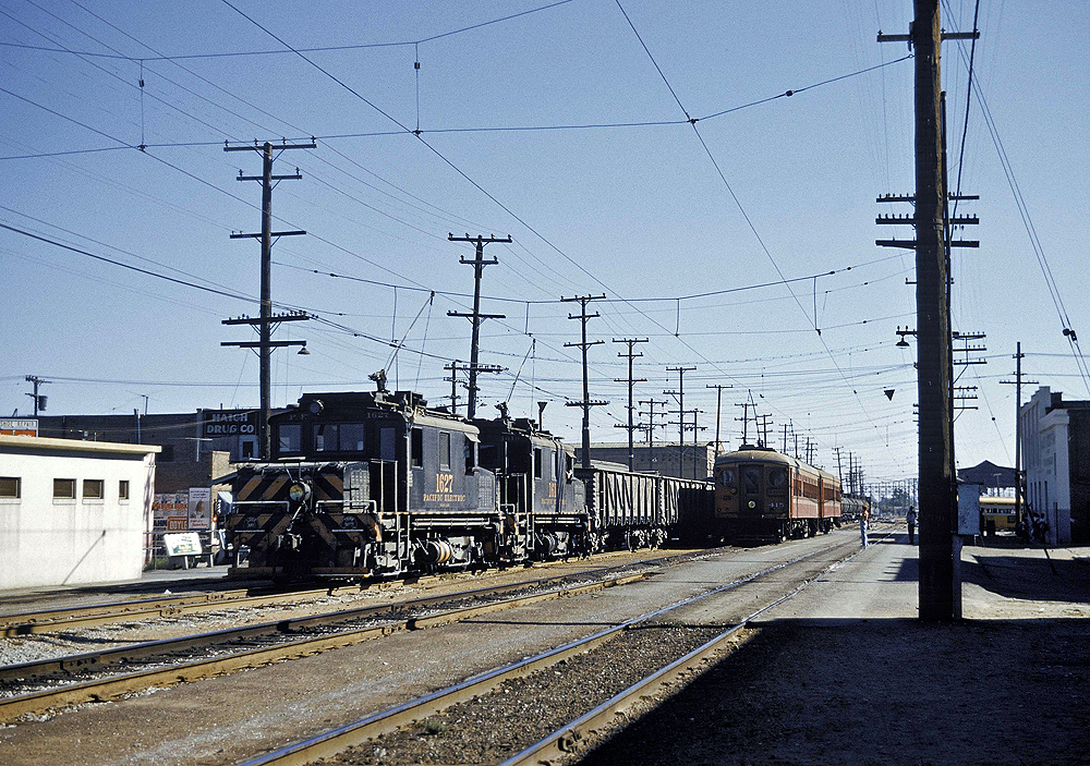 Freight motors lead a train through an industrial area.