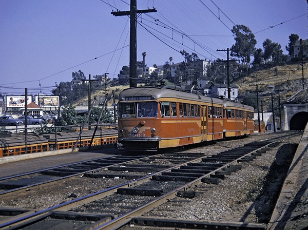 A pair of couples streetcars or interurban cars exit a tunnel.