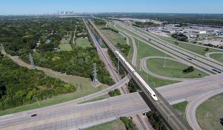 Birds eye view of a rail line passing over a complex highway interchange.