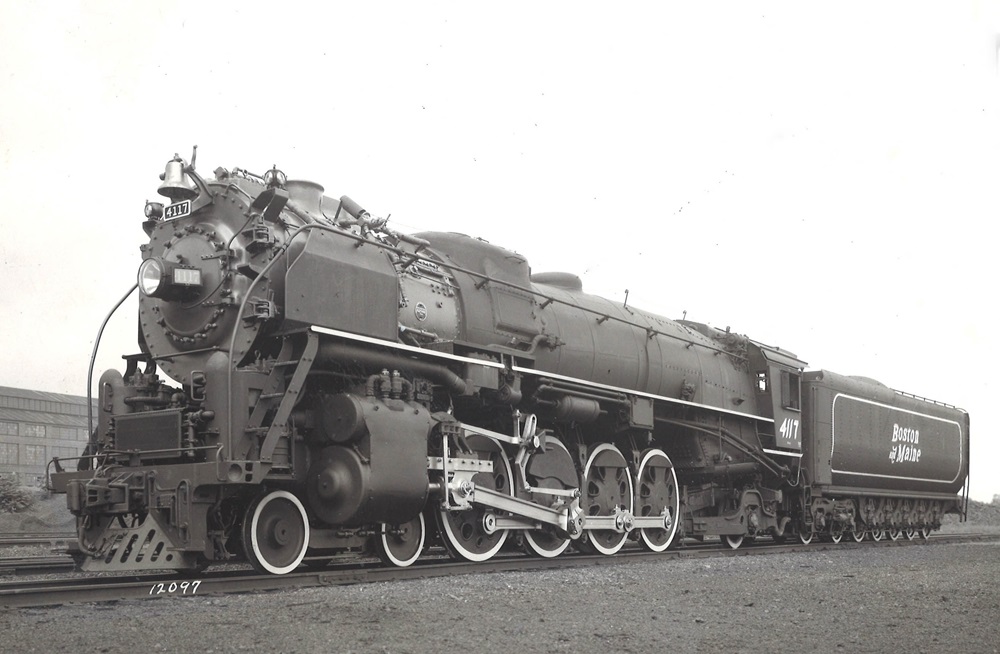 An oblique front view of a 4-8-2 steam locomotive in a rail yard.
