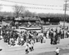 A crowd of people surrounds a platform and steam locomotive on display.