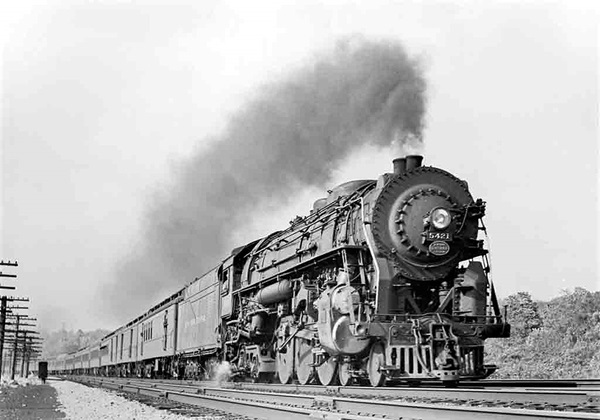 Steam locomotive at speed with passenger train.