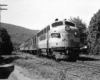 One cab unit style diesel locomotive leading a passenger train.