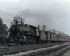 A steam locomotive leading a long passenger train over a multi-track mainline.