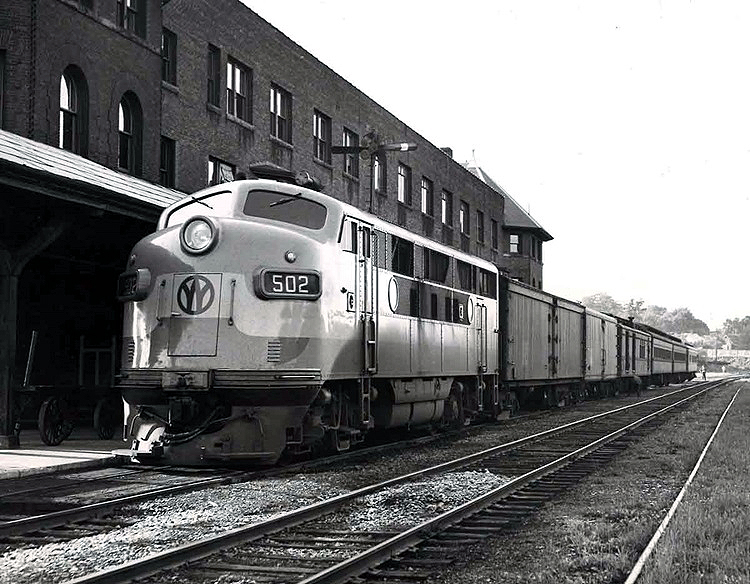 A cab diesel locomotive at the head of a express and passenger-car train.