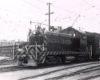 A three-quarter wedge view of a diesel locomotives hauling a boxcar in a yard.