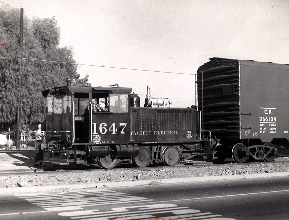 A small gas-powered locomotive hauls a boxcar.