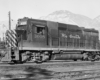 Side view of a four-axle diesel locomotive with mountains in the background.