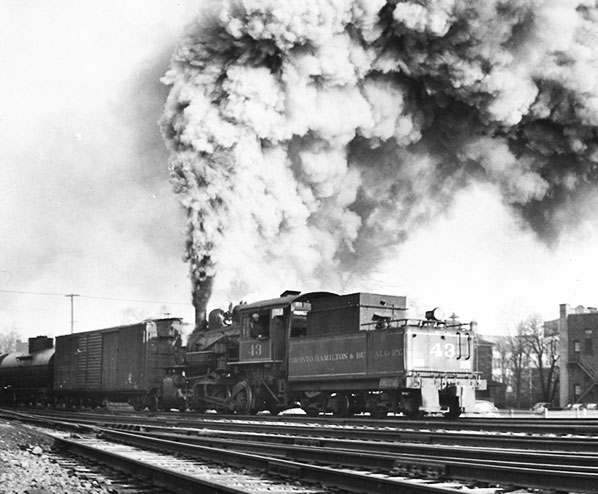 a black and white image of a steam locomotive and a large plum of steam