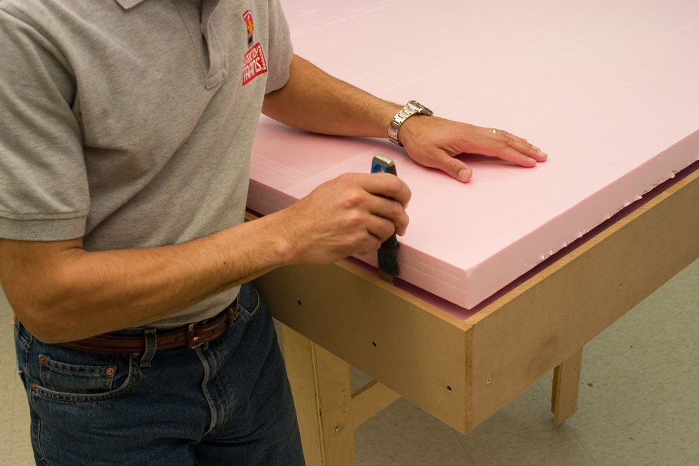 Man building model railroad layout working with pink extruded foam board.