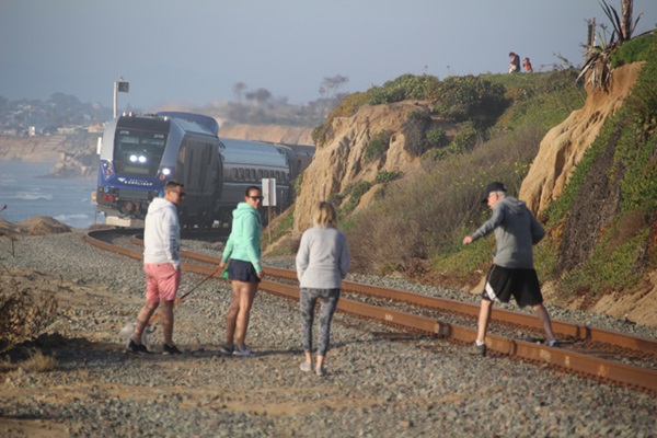 People walking on railroad tracks as train approaches