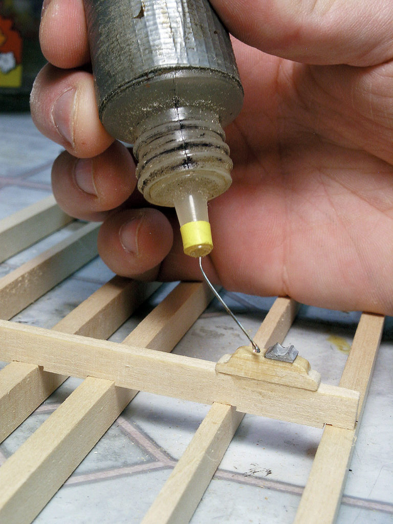 Dripping cyanoacrylate accelerator on a wood joint with a needle-tipped bottle wrapped with duct tape.