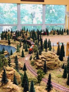 A model train pulling cars through the hilly landscape.