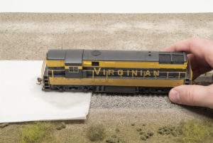 Bachmann HO scale Virginian Ry. Fairbanks-Morse H-16-44 diesel locomotive with rear truck on towel wetted with isopropyl alcohol and front truck on rails.