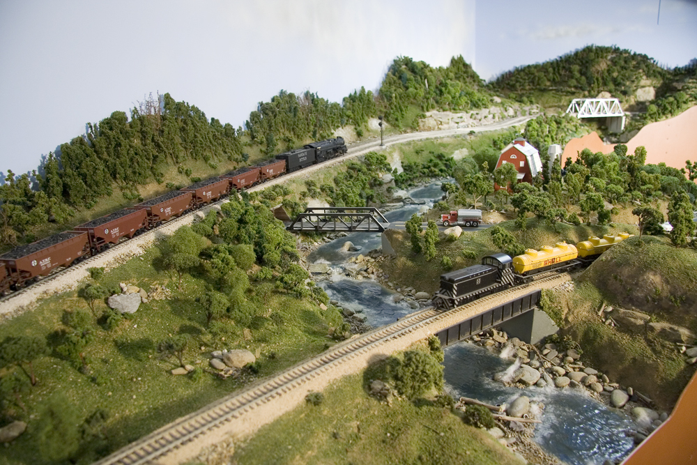 A slight overhead view of a mainline and siding with two Santa Fe trains in HO Scale.