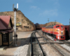 A two-one orange Southern Pacific passenger train glides through a high-desert southern California scene depicting Cajon Pass.