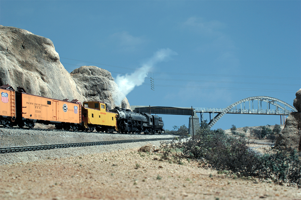 A Union Pacific refrigerated boxcar train gets pushed upgrade in a desert scene west of California's Cajon Pass.