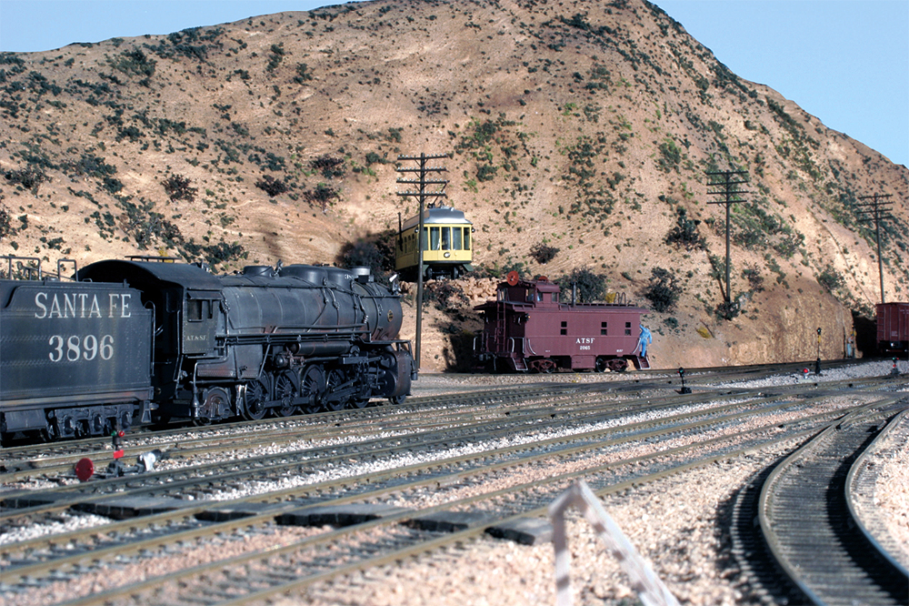 A Santa Fe steam locomotive and caboose are posed at Gary Hoover's HO Scale representation of "Summit", the top of the grade for the Santa Fe in California's Cajon Pass.