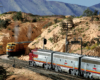 A Union Pacific train nears the top of the grade in an arid scene at "Summit" in Cajon Pass while a Santa Fe steam locomotive idles near the dispatcher's station.