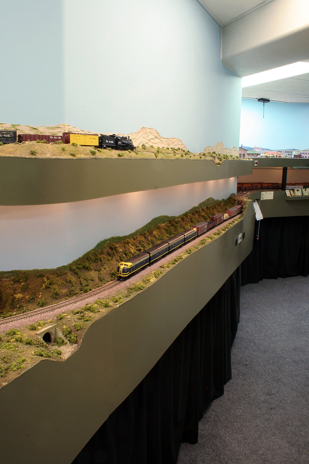 A vertical photo showing narrow gauge Rio Grande trains on an upper level of the layout and standard gauge Santa Fe trains underneath.