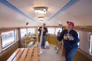 People painting a train car ceiling