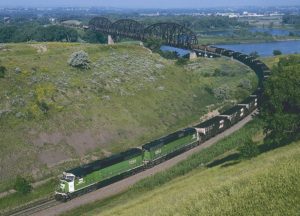 Train coming off bridge on broad curve