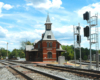 A gothic revival passenger train station at the junction of two double-track lines.