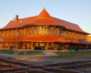 An old-style rounded train station at a diamond in low-angle sunlight under clear skies.