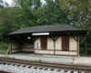 A dilapidated wood shelter next to railroad tracks.